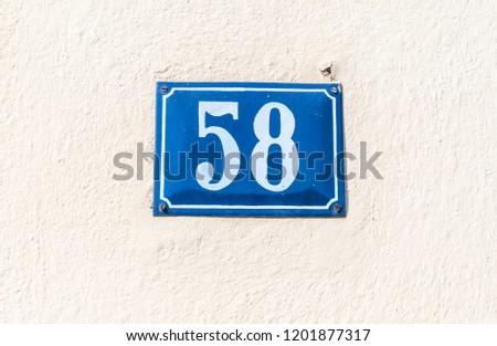 Old vintage house address blue metal plate number 58  fifty eight on the plaster facade of abandoned home exterior wall on the street side