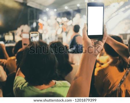 Hands with mobile smart phone recording and taking a picture at music concert