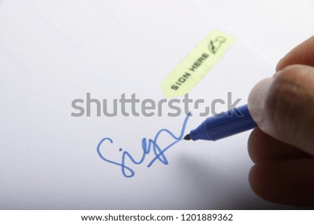 signing on white paper with blue marker