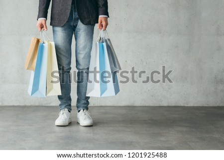 shopaholic and consumerism concept. multiple bags with goods from stores in man hands.
