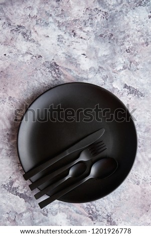 Top view of black empty round plate and tableware on marble stone background
