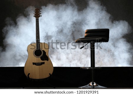 Guitar with white smoke. With the long chair on the black floor.