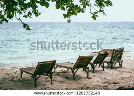 Tropical beach with Blue sky and clear sea which including of a wooden umbrella and chair in sunrise time with vintage retro tone. Vacation time as concept.