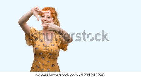 Young redhead woman smiling making frame with hands and fingers with happy face. Creativity and photography concept.