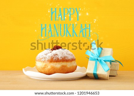 Image of jewish holiday Hanukkah with present box and traditional doughnut on the table