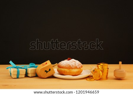 Image of jewish holiday Hanukkah with traditional doughnut and spinning top on the table