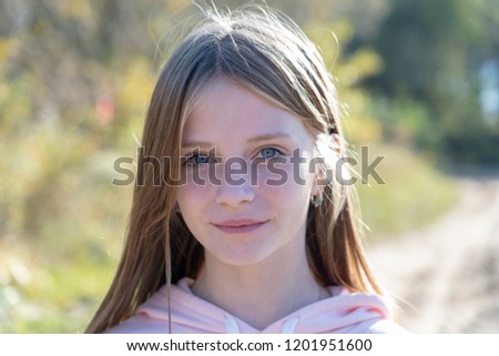 Beautiful blonde young girl with freckles outdoors on nature background in autumn, close up portrait