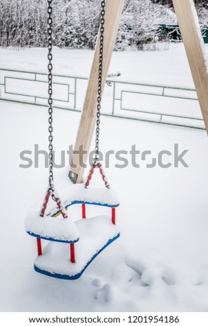 Close up view of empty swings in the city street on a winter snowy day
