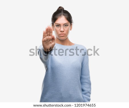 Young beautiful hispanic woman wearing a bun with open hand doing stop sign with serious and confident expression, defense gesture