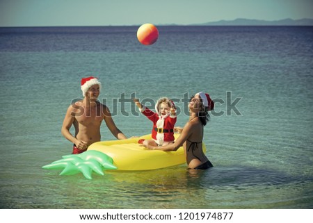 Winter holiday vacation. Santa child, parents at Christmas. Xmas party celebration, fathers and mothers day. New year man, girl with small boy. Christmas happy family on pineapple mattress in water.