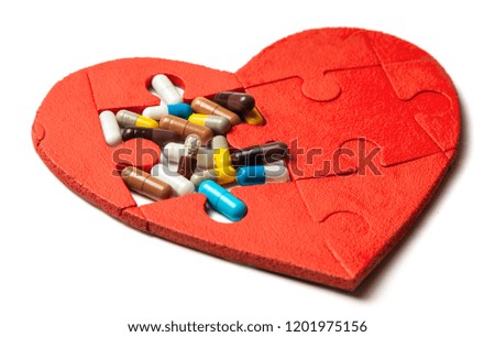 Heart puzzle red and colored pills and capsules isolated on white background. Concept treatment of heart disease pills