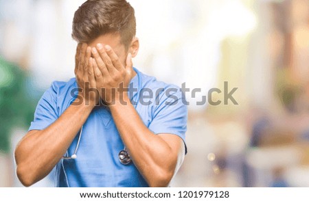 Young handsome doctor surgeon man over isolated background with sad expression covering face with hands while crying. Depression concept.