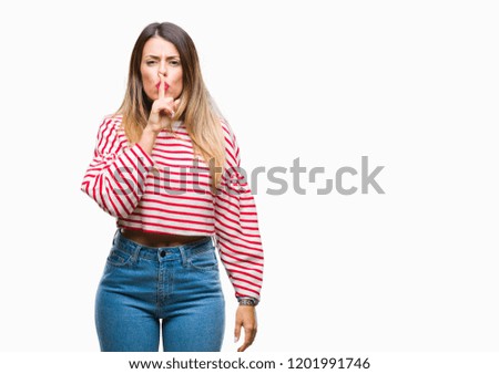 Young beautiful woman casual stripes winter sweater over isolated background asking to be quiet with finger on lips. Silence and secret concept.