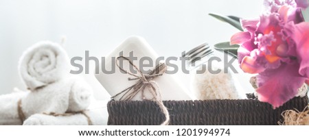 Spa items in a wicker stand on a light background with a tropical orchid, body care concept