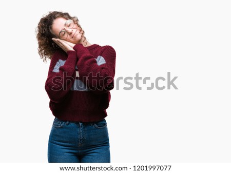 Beautiful brunette curly hair young girl wearing glasses over isolated background sleeping tired dreaming and posing with hands together while smiling with closed eyes.