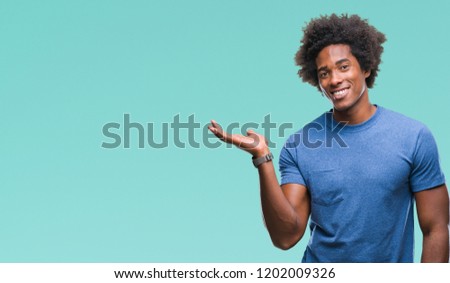 Afro american man over isolated background smiling cheerful presenting and pointing with palm of hand looking at the camera.