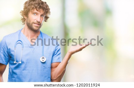 Handsome hispanic surgeon doctor man over isolated background smiling cheerful presenting and pointing with palm of hand looking at the camera.