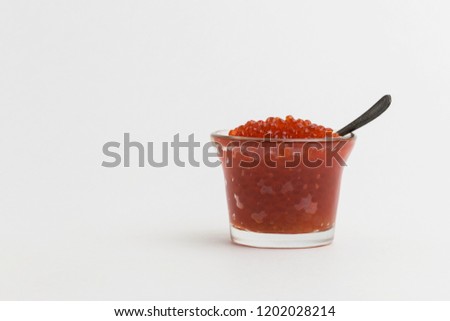 Luxurious delicious. Red caviar in glass with spoon on white background