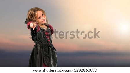 Kid dressed as a vampire at halloween holidays points finger at you at outdoor with sunset
