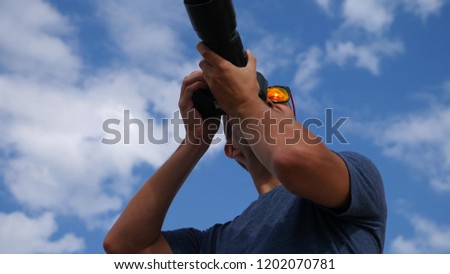 A close-up of a male photographer is taking pictures in the street with the help of a professional camera.
