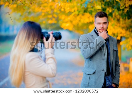 Young photographer with camera  and model in autumn season outdoor.
