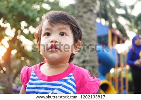 Potrait of Cute Asian Kid Girl on outdoor playground in the evening over sun ray background. Summer Leisure for kids
