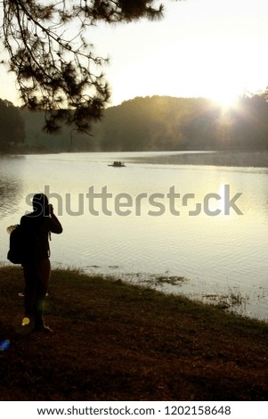 Young man who was taking a photo tourist's raft in lake in morning winter time,Pang-Ung,Thailand.
