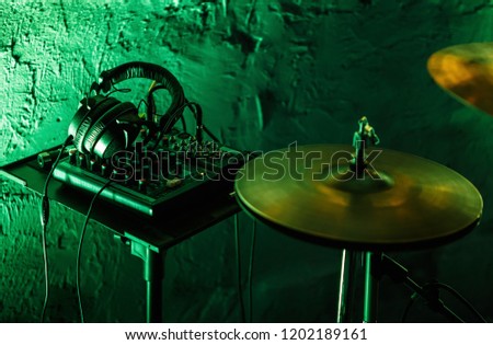 Professional drummer audio equipment for playing live music on rock concert.Drum kit cymbals and stereo headphones monitors in bright green stage lights in night club