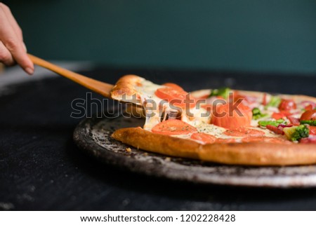 Hot pizza slice with melting cheese on a rustic black table