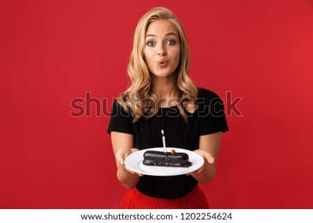 Image of young happy woman showing birthday sweetie on plate isolated over red background.