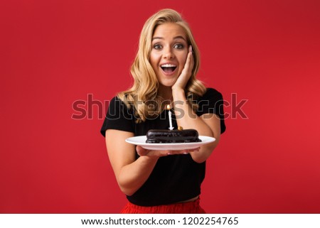 Image of young happy woman showing birthday sweetie on plate isolated over red background.