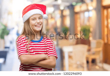 Young beautiful girl wearing christmas hat over isolated background happy face smiling with crossed arms looking at the camera. Positive person.