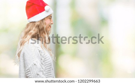 Beautiful young blonde woman wearing christmas hat over isolated background looking to side, relax profile pose with natural face with confident smile.
