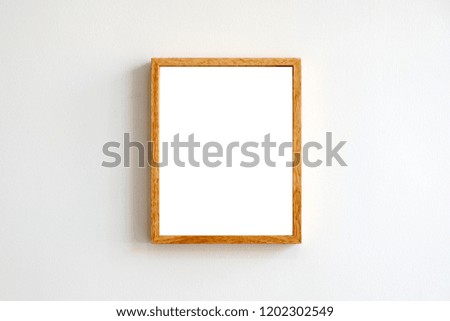 A blank wooden picture frame on white wall background