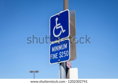 A sign about fines at parking lot for disabled people.