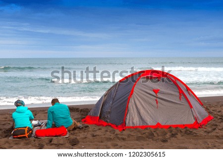 a pair of tourists with a tent near the ocean