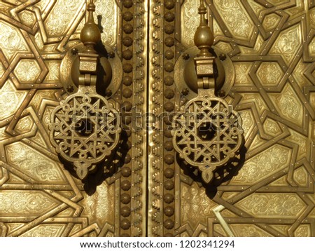 Ornamented golden door with geometric pattern and handles/knockers - Royal Palace in Fes, Morocco, Africa.