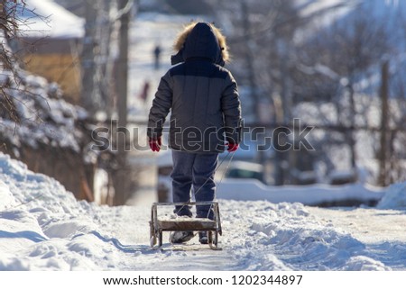 Boy with sled in the snow in winter