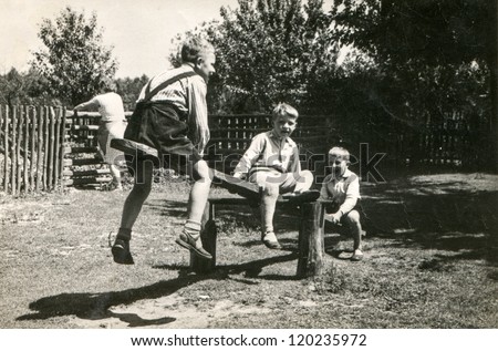Vintage photo of boys playing on wooden swing (fifties)