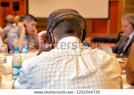 Unrecognizable people using in ear headphones for translation during event and meeting