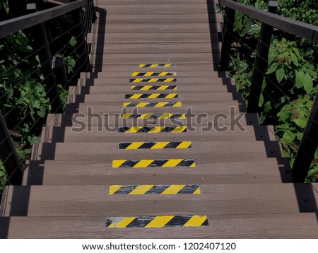 Wooden stairs or walkway go down to outdoor garden surrounded with green trees. Be careful when you walk.       