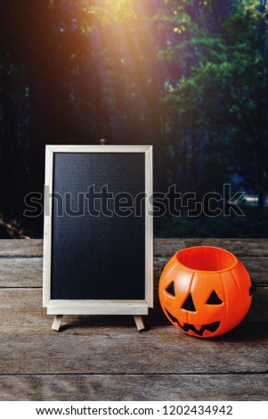Halloween background. Spooky pumpkin, chalkboard on wooden floor with moon and dark forest. Halloween design with copyspace
