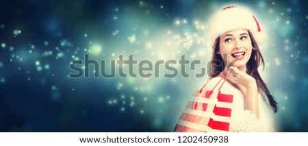 Happy young woman holding a shopping bag in snowy night