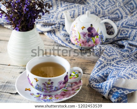 Home interior decor, bouquet of mauve flowers in a vase and blue fabric on rustic wooden table with set of teapot. Royalty-Free Stock Photo #1202453539