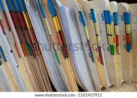 A close-up look of the color-coded and numbered folders in wall shelves showing the medical records of patients from the office of a clinic in horizontal format.
