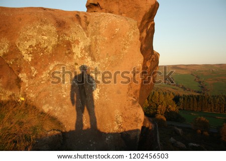 The silhouette of a man on rocks at sunset in the peak district Staffordshire England UK 