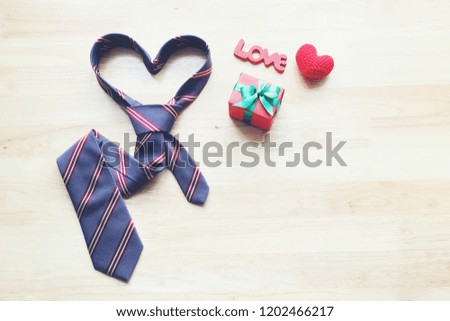 Heart necktie and gift box with ribbon and handmade crochet heart on wood background for happy fathers day 