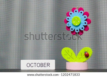 Beautiful flower handmade by colorful felt fabrics and month of October on wooden  block calendar