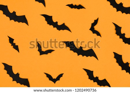 halloween decorations concept, many black paper bats on orange background, table top view, lots of free space