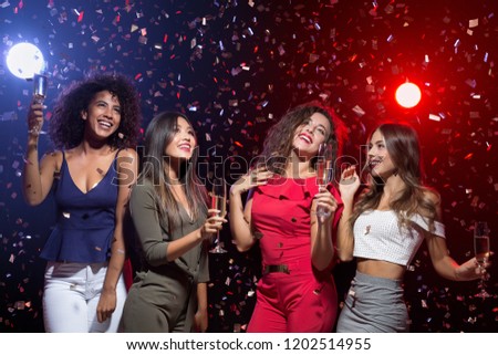 Stylish women celebrating new year, having fun, dancing and drinking alcohol cocktails at nightclub, copy space.